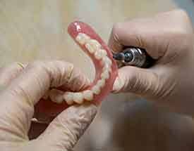 Lab technician filing dentures