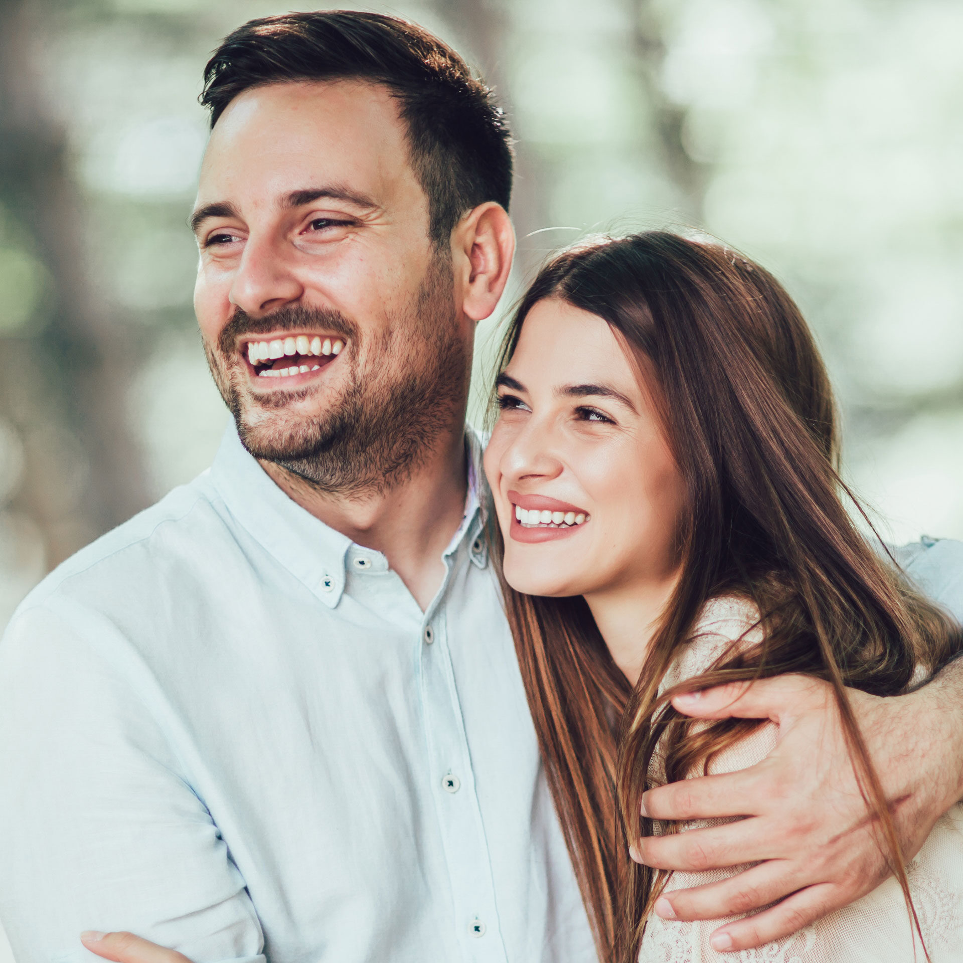 happy couple hugging and smiling in the park